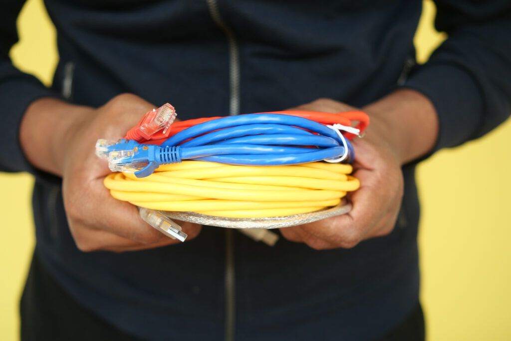 Un primer plano de manos que sostienen un cable Ethernet azul enrollado para una conexión de red.