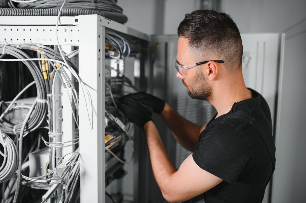 DECU Un técnico trabaja con servidores en un centro de datos. Un hombre conecta cables en una sala de servidores.